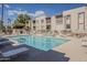 Inviting community pool area featuring ample seating, a grilling area, and well-maintained landscaping under a clear blue sky at 205 N 74Th St # 227, Mesa, AZ 85207