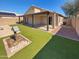 Artificial grass and a covered patio create a low maintenance backyard oasis perfect for relaxing at 24811 W Wayland Dr, Buckeye, AZ 85326