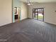 Spacious living area with carpet, ceiling fan, sliding glass doors to the backyard and an archway to the bathroom at 24811 W Wayland Dr, Buckeye, AZ 85326