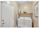 Functional laundry room includes washer, dryer, a shelf with cleaning supplies, an ironing board and a door to outside at 36199 W Prado St, Maricopa, AZ 85138