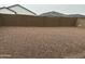 Large backyard space with gravel cover, enclosed by a tall block fence for privacy and low maintenance at 40816 W Sunland Dr, Maricopa, AZ 85138