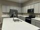 Modern kitchen features stainless steel appliances, gray cabinets, and a white quartz countertop island at 40816 W Sunland Dr, Maricopa, AZ 85138