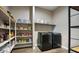 Well-organized pantry and laundry room with ample shelving and storage, plus modern black washer and dryer units at 40816 W Sunland Dr, Maricopa, AZ 85138