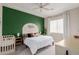 Bright bedroom with a green accent wall, fan, white bedding, and a crib at 4241 N Pebblecreek Pkwy # 7, Goodyear, AZ 85395