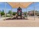Community playground featuring a covered structure, play equipment, and mature trees, creating an inviting space at 4241 N Pebblecreek Pkwy # 7, Goodyear, AZ 85395