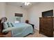 Bright bedroom featuring a ceiling fan, a view to the outside, and a wooden dresser with a mounted TV at 44421 N 12Th St, New River, AZ 85087