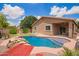 Inviting backyard oasis featuring a refreshing pool, lush greenery, and a covered patio at 45309 W Gavilan Dr, Maricopa, AZ 85139