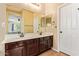 Bathroom vanity featuring dual sinks, a large mirror, and dark wood cabinets at 45309 W Gavilan Dr, Maricopa, AZ 85139