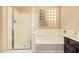 Bathtub and shower combo with glass shower door and glass block window at 45309 W Gavilan Dr, Maricopa, AZ 85139