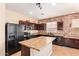 Kitchen featuring stainless steel appliances, central island, tile floors and brick accent wall at 45309 W Gavilan Dr, Maricopa, AZ 85139