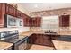 A lovely kitchen with stainless appliances, dark cabinets, a brick wall, and tile flooring at 45309 W Gavilan Dr, Maricopa, AZ 85139