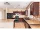This home's kitchen features dark cabinets, tile floors, stainless steel appliances, and a brick wall at 45309 W Gavilan Dr, Maricopa, AZ 85139