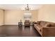 Cozy living room with dark hardwood floors, a comfortable brown sofa, and ample natural light from the window at 45309 W Gavilan Dr, Maricopa, AZ 85139
