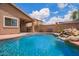 Stunning backyard pool featuring an outdoor kitchen area and a relaxing rock waterfall at 45309 W Gavilan Dr, Maricopa, AZ 85139