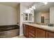 Bathroom featuring dual sinks with granite countertops, a soaking tub, and modern lighting fixtures at 5350 E Deer Valley Dr # 1433, Phoenix, AZ 85054
