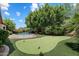 Lush backyard with a putting green, swimming pool, and mature trees at 6438 E Claire Dr, Scottsdale, AZ 85254