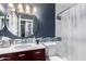 Well-lit bathroom with blue accent wall, a large round mirror, and bathtub with glass shower curtain at 7500 E Deer Valley Rd # 157, Scottsdale, AZ 85255