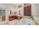Stylish bathroom features a soaking tub, double mirror, tile floor, and vanity at 7841 E Stonecliff Cir, Mesa, AZ 85207