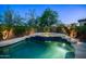Pool area illuminated at dusk, showcasing the waterfall and mature landscaping at 7841 E Stonecliff Cir, Mesa, AZ 85207