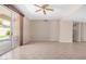 Spacious, empty living room featuring tile floors, a ceiling fan, and sliding glass doors to the yard at 8874 W Piute Ave, Peoria, AZ 85382