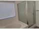 Bright bathroom featuring a bathtub, glass-enclosed shower and window with blinds at 8927 W Paradise Dr, Peoria, AZ 85345
