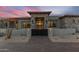 Inviting entrance with a stone facade, black gate, and desert landscaping, creating a grand arrival at 9456 E Sands Dr, Scottsdale, AZ 85255