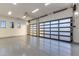 Spacious garage with epoxy flooring, bright lighting, and glass panel doors at 9456 E Sands Dr, Scottsdale, AZ 85255