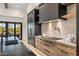 Modern kitchen with custom cabinets, black countertops, a range hood, and stainless steel appliances at 9456 E Sands Dr, Scottsdale, AZ 85255