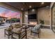 Expansive outdoor living space featuring a fireplace, TV, comfortable seating, and views of the desert sunset at 9456 E Sands Dr, Scottsdale, AZ 85255