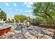 Backyard with built-in firepit and lounge chairs with pool in the background and lush landscaping at 10040 E Happy Valley Rd # 243, Scottsdale, AZ 85255