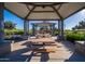 Under the roof of the picnic area, you see many picnic tables and play ground at 10860 E Tiburon Ave, Mesa, AZ 85212