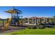 Neighborhood playground with a colorful play structure, picnic tables, shaded pavilions, and green lawn at 10905 E Texas Ave, Mesa, AZ 85212