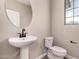 Modern powder room featuring a pedestal sink, round mirror, toilet, and sleek black fixtures at 15599 S 180Th Ln, Goodyear, AZ 85338