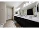 This bathroom has a double sink vanity with framed mirrors and a tiled floor at 16930 W Woodlands Ave, Goodyear, AZ 85338