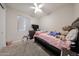 This cozy bedroom features a full sized bed, a ceiling fan, and carpeted floors at 16930 W Woodlands Ave, Goodyear, AZ 85338