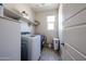 Practical laundry room featuring washer, dryer, shelving and a bright window at 16930 W Woodlands Ave, Goodyear, AZ 85338