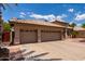 Spacious three-car garage with tan exterior, tile roof, and ample parking space on a sunny day at 1884 E Stephens Dr, Tempe, AZ 85283