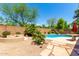Backyard featuring a firepit, patio, and pool surrounded by lush greenery and mature trees at 194 E Canyon Creek Dr, Gilbert, AZ 85295