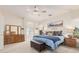 A serene main bedroom with a plush bed, dresser, ceiling fan, and natural light from the adjacent bathroom at 194 E Canyon Creek Dr, Gilbert, AZ 85295
