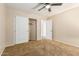 A beige bedroom includes a ceiling fan, tan carpet, and a sliding door closet at 2556 E Quiet Hollow Ln, Phoenix, AZ 85024