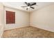 A beige bedroom includes a ceiling fan, a window with blinds, neutral colored walls, and tan carpeting at 2556 E Quiet Hollow Ln, Phoenix, AZ 85024