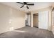 A beige bedroom includes a ceiling fan, tan carpet, and a closet at 2556 E Quiet Hollow Ln, Phoenix, AZ 85024
