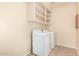 Clean laundry room with white washer and dryer and built-in shelves for storage at 2556 E Quiet Hollow Ln, Phoenix, AZ 85024