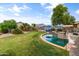 Large backyard featuring an inviting pool, lush lawn, mature trees, and a cozy lounge area at 35952 W Catalonia Dr, Maricopa, AZ 85138