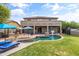 Expansive backyard with a sparkling pool, covered patio with fire pit, and beautifully landscaped yard at 35952 W Catalonia Dr, Maricopa, AZ 85138