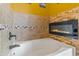 Large soaking tub with decorative stone wall, tile surround, and a sleek black fixture at 35952 W Catalonia Dr, Maricopa, AZ 85138