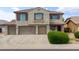 Beautiful two-story house featuring a three-car garage, stone details, shutters, and manicured landscaping at 35952 W Catalonia Dr, Maricopa, AZ 85138