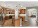 Open concept kitchen with wood cabinets, granite countertops, center island, stainless appliances, and stylish pendant lights at 35952 W Catalonia Dr, Maricopa, AZ 85138