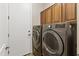 Modern laundry room featuring updated washer and dryer appliances and ample cabinet space at 35952 W Catalonia Dr, Maricopa, AZ 85138