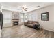 Spacious living room with a brick fireplace, modern ceiling fan, and a comfortable sofa at 35952 W Catalonia Dr, Maricopa, AZ 85138
